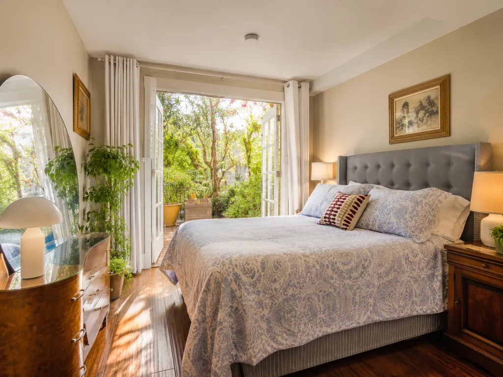 A bedroom with a bed, nightstands, lamps, and a large mirror.